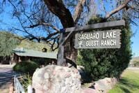Sign for Saguaro Lake Guest Ranch with building behind it.